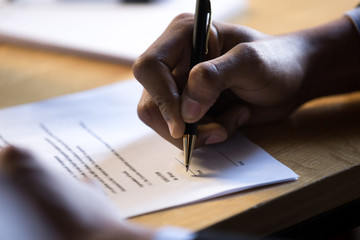 Male african hand signing financial contract concept, black businessman put write signature on...