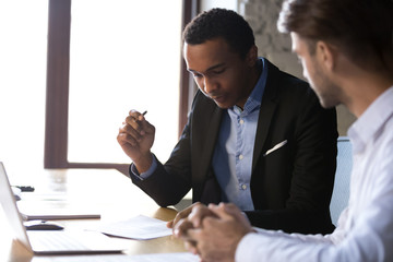 African american businessman reading documents at meeting, black client or customer considering contract terms before signing checking legal paper law conditions preparing to make financial deal