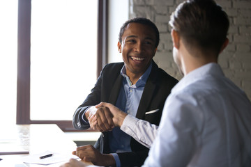 Happy satisfied black client shaking hands thanking manager for good financial deal, african...