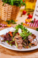 Salad with fried meat, pine nuts, vegetables and mozzarella cheese on white plate. Close up