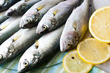 Fresh fish with the vegetables, condiment and lemon, bluefish. Food preparation.
