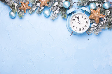 Blue alarm clock,  branches fir tree, box with present and golden stars on  blue textured  background.