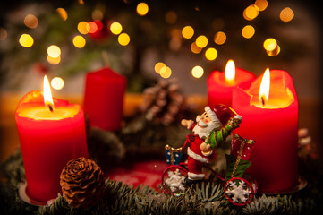 Fototapeta na wymiar Adventskranz mit 3 brennenden Kerzen und Weihnachtsmann auf Fahrrad im Endspurt
