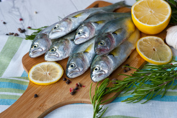 Fresh fish with the vegetables, condiment and lemon, bluefish. Food preparation.
