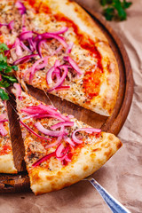 Pizza with tuna and red onion on wooden cutting board. Close up