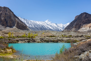Fototapeta na wymiar Panorama shot of small turquoise mountain lake under the sunny day with blue sky along Karakorum Highway in Passu, Hunza district of Pakistan.