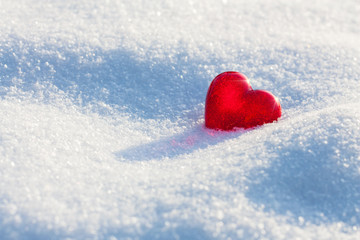 Single red heart on snow. Valentine day, love concept. Deep blue shadows, space for text, selective focus