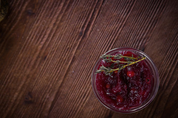 Cowberry sauce in a glass bowl on a wooden table