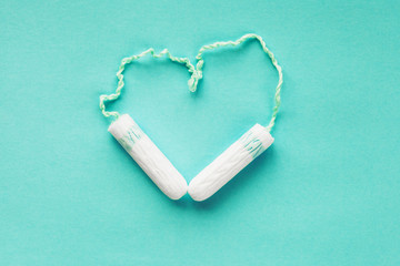 tampons on mint background shaped as heart, intimate female health care