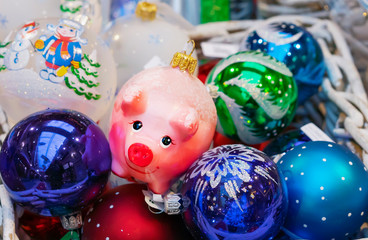 Christmas glass toy pink piggy among colorful balloons.