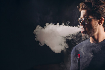 young awesome man is addicted to a hookah. close up side view photo. copy space. thick smoke from the hooka