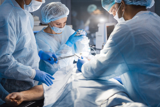 Attentive medical workers operating their patient. A surgery like this requires an anesthesiologist, a general surgeon to remove tumor and, at least two surgical nurses.