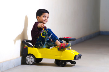 asian baby boy rides his toy car