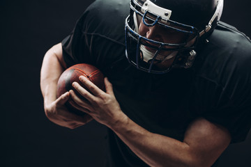 American football player with helmet and armour passing a ball while running on field at night