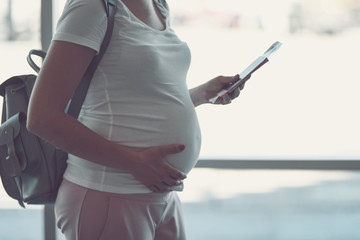 Pregnant woman is traveling by plane standing near the window