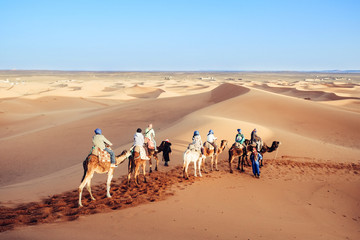 Tourists enjoying with camel caravan in the Sahara desert. Erg Chebbi, Merzouga, Morocco.