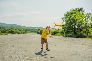 Happy kid playing with toy airplane against old runway background. Traveling with kids concept