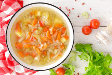 Vegetable soup. Healthy food, vegetarian dish. Vegetable soup with cabbage, potato, tomato, carrot, celery, pepper and green peas. Vegan diet menu. Top view