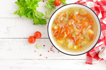 Vegetable soup. Healthy food, vegetarian dish. Vegetable soup with cabbage, potato, tomato, carrot, celery, pepper and green peas. Vegan diet menu. Top view