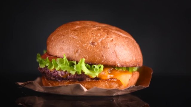 Cheeseburger rotated on black background. Fresh Hamburger on fresh buns with succulent beef and fresh salad ingredients isolated on black. Slow motion. 3840X2160 4K UHD video footage