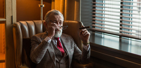 Mature experienced male professor wears formal costume, eyewear, looks confidently, has clever...