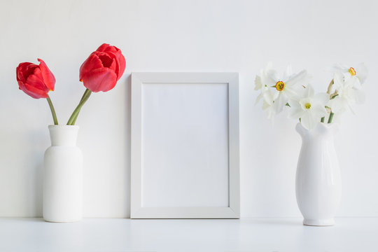 Mockup with a white frame and red tulips in a vase on a light background