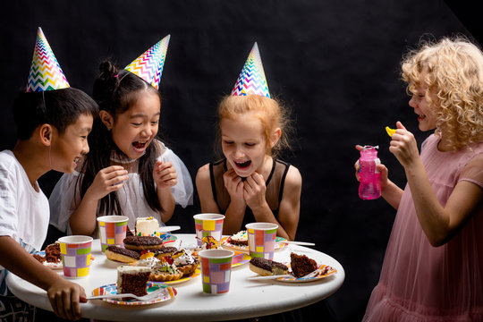 funny laughing kids are looking at the bursted bubbles. fun and game concept. close up photo. isolated black background