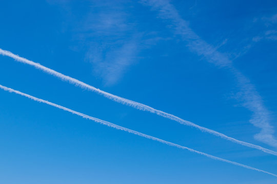 Blue sunny sky with light clouds and traces of flying aircraft