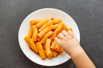 Little child eats fresh pasta with tomato sauce parmesan cheese