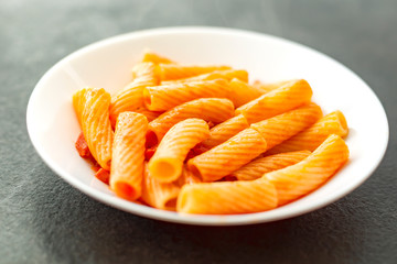 Penne Amatriciana fresh pasta with parmesan cheese on dark backg