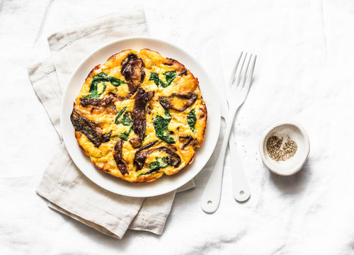 Porcini mushrooms, potatoes, spinach baked frittata - delicious breakfast, snack, tapas on a light background, top view