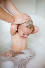 Fototapeta premium Cute two year old boy taking a relaxing bath with foam