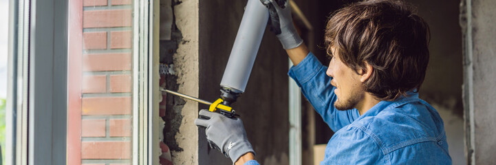 Man in a blue shirt does window installation. Using a mounting foam BANNER, LONG FORMAT
