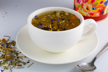 Black tea in glass cup with mint. Tea leaves in wooden spoon. On white, isolated background