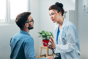 Woman Doctor talking to Patient at her Medical Office