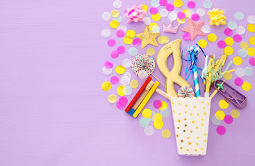 Purim celebration concept (jewish carnival holiday) over purple, pink wooden background. Top view.