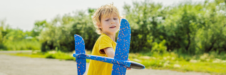 Happy kid playing with toy airplane against old runway background. Traveling with kids concept BANNER, LONG FORMAT