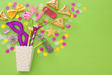 Purim celebration concept (jewish carnival holiday) over green wooden background. Top view.