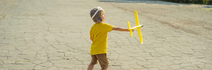 Happy kid playing with toy airplane against old runway background. Traveling with kids concept BANNER, LONG FORMAT
