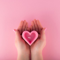 Heart shaped pink candle in female hands