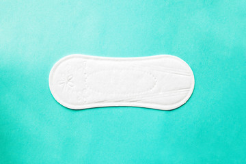 soft clean cotton menstruation pad lying on mint background, women critical days, gynecological menstruation cycle