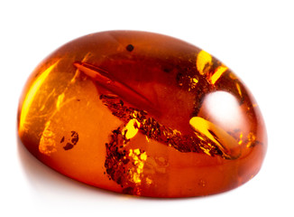Polished cabochon of artificial amber with inclusions on white background isolated