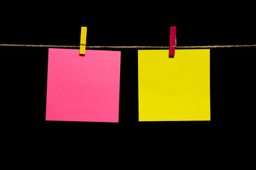 Copy space. Two sheets of paper yellow and pink with clothespins hang on a rope.