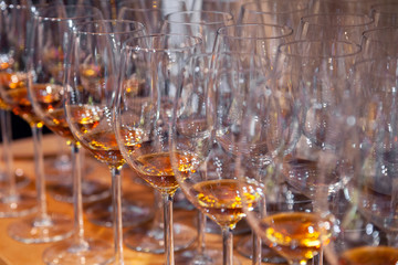 Closeup wine glasses with cognac stand in row on wooden shelves. Side view. Concept of degustation spirits: whiskey, brandy, porto, bitter, sherry on bartenders sommelier competition, exhibition