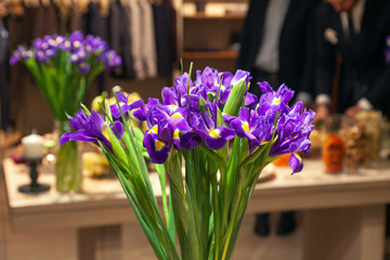 Closeup bouquet of fresh flowers purple irises with yellow details stand in glass vase. Сoncept of opening florist shop, fresh flower decor whiskey tasting