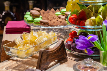 Closeup of fresh honeycombs cut into cubes in transparent square glass bowl at buffet, cinnamon...