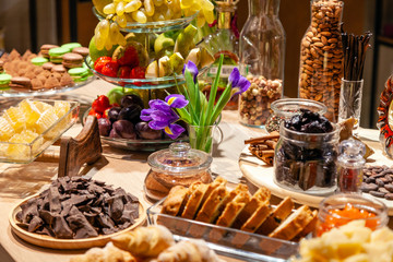 Closeup snacks, fresh and dried fruits, pieces parmesan cheese, honeycombs, dark chocolate, cinnamon sticks, nuts, biscotti. Concept degustation premium alcohol at opening of the clothes store