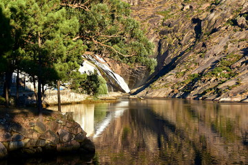 Fototapeta na wymiar Mountain, trees, river and waterfall with water reflections and sunset light. Ezaro, Galicia, Spain.