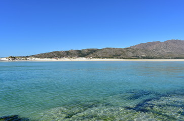 Fototapeta na wymiar Beach with clear and turquoise water and small mountain. Sunny day, blue sky. Galicia, Spain.