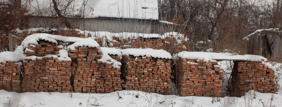 outdoor warehouse Wooden pallet of the red bricks covered snow on an another such pallet
